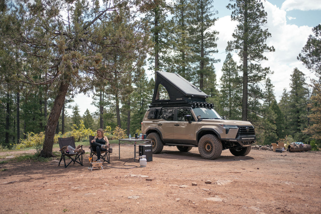 Camp setup with the GX 550 fully equipped. The SUV is equipped with off road bumpers, roof rack, tent, light brackets, and molle panels from Rago Fabrication.