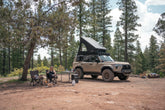 Camp setup with the GX 550 fully equipped. The SUV is equipped with off road bumpers, roof rack, tent, light brackets, and molle panels from Rago Fabrication.